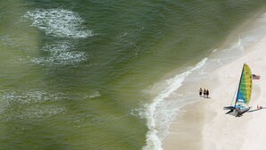 Uma praia com um veleiro e pessoas caminhando pela margem.