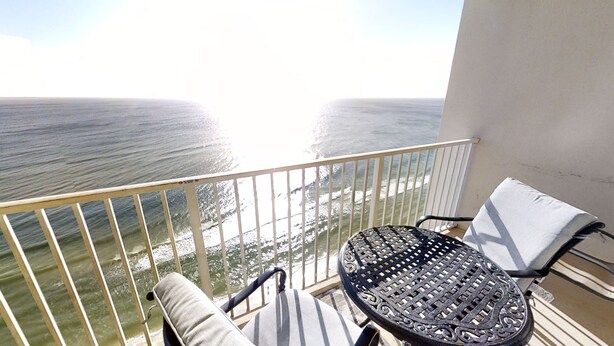 Varanda com vista para o oceano, uma mesa e duas cadeiras.