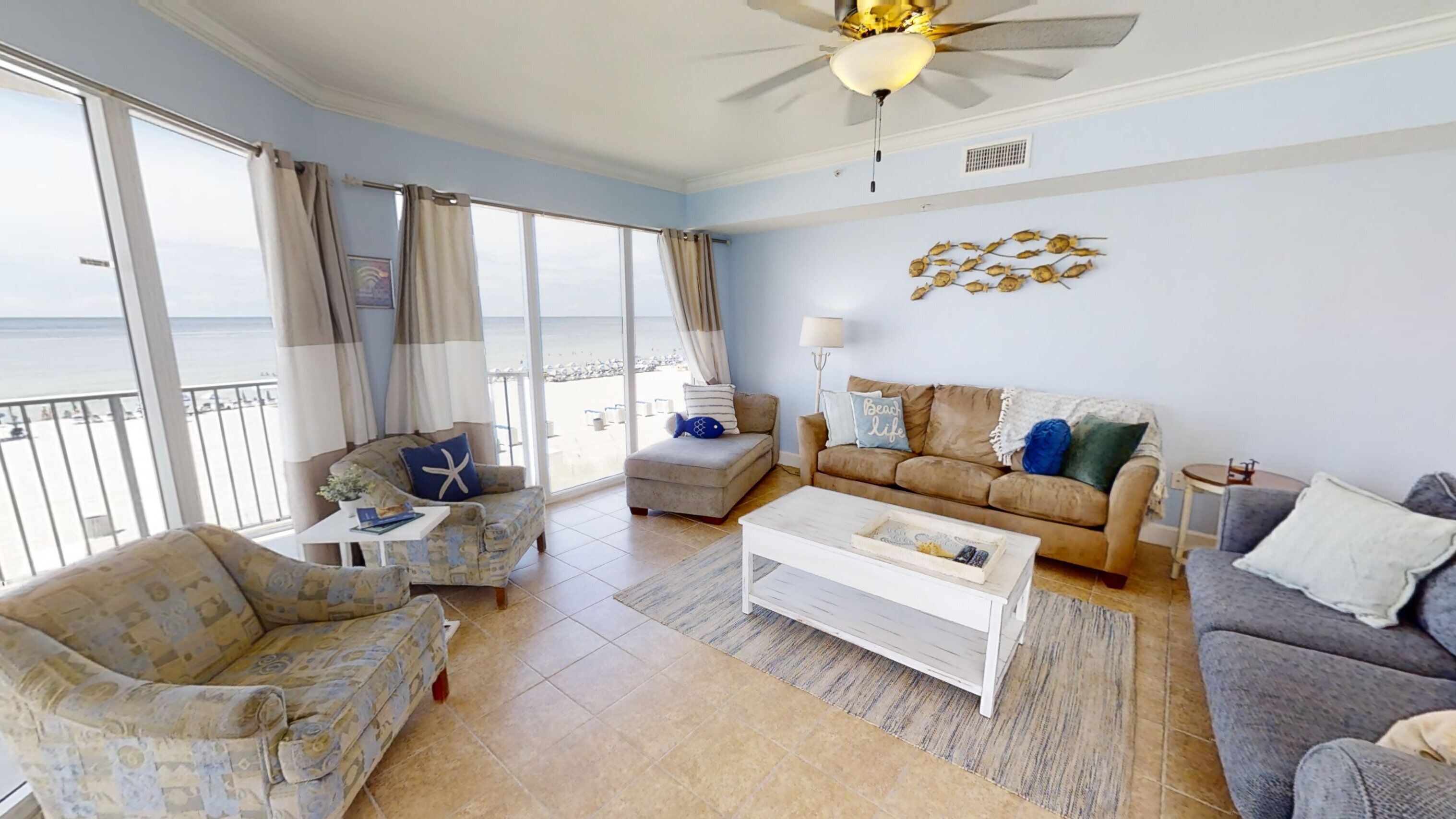 A spacious living room with a view of the sea, furnished with a sofa, armchair, and coffee table.