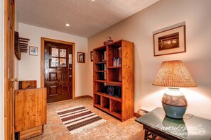 Enter a warm and inviting space with a beautifully appointed entryway featuring a wooden door, bookshelf, and stylish table.