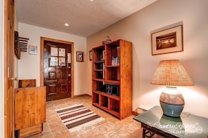Enter a warm and inviting space with a beautifully appointed entryway featuring a wooden door, bookshelf, and stylish table.