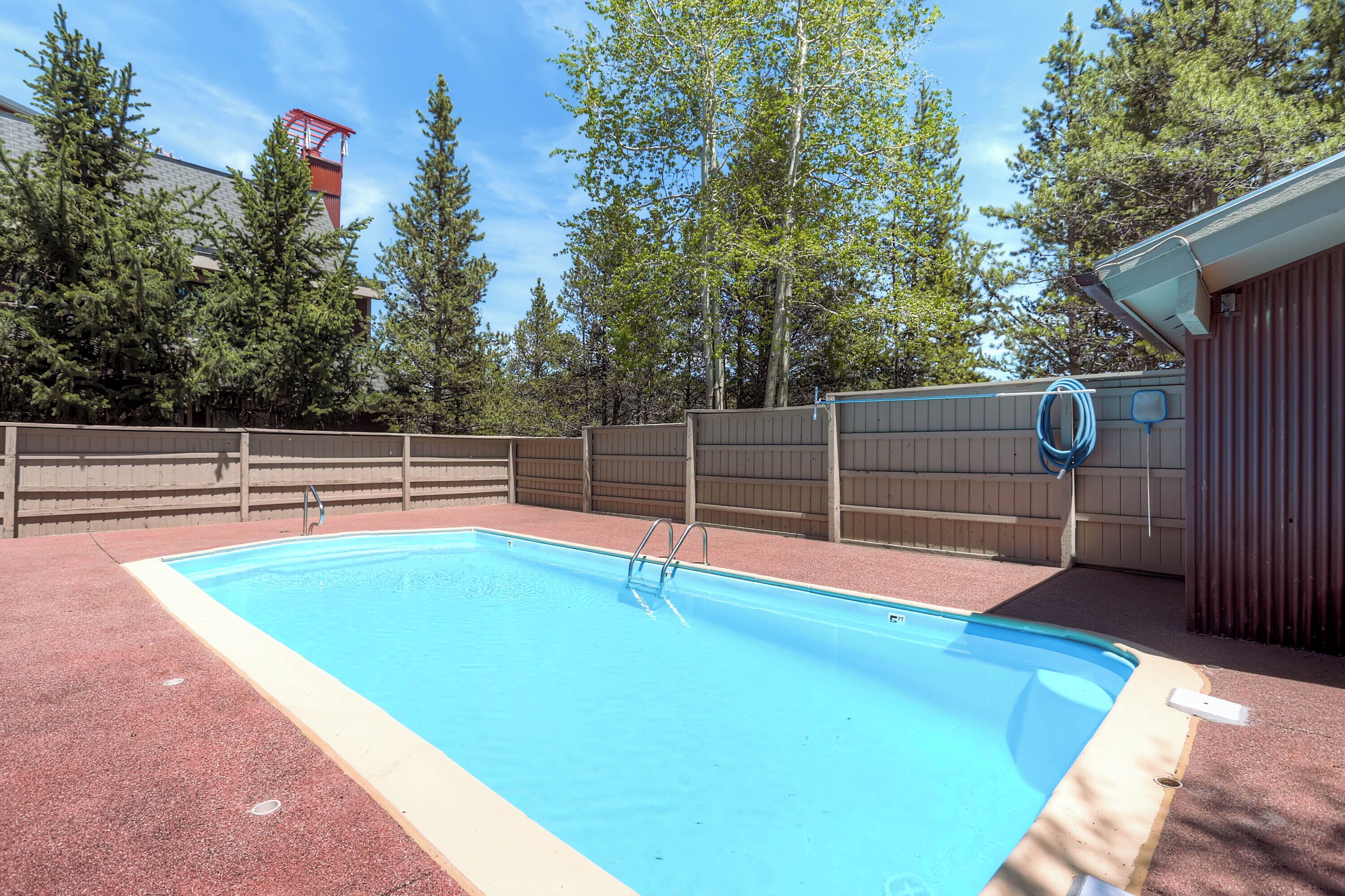 A rectangular swimming pool with a wooden deck and a metal ladder.