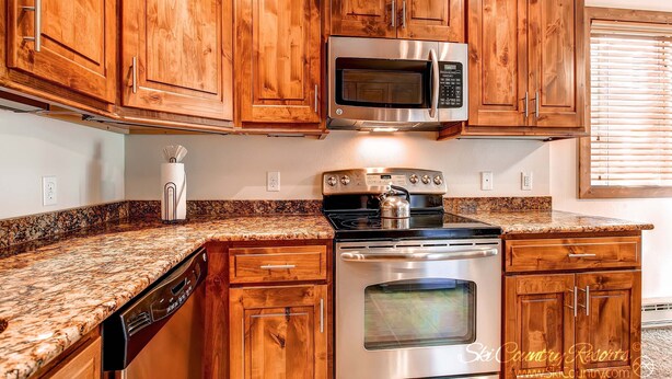 A kitchen with wooden cabinets, a stainless steel microwave, an oven, and a dishwasher. - A Downtown Breck Oasis. Enjoy Convenience with Onsite Pool sh15 (Breckenridge)