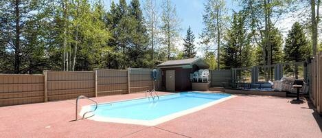 En trädgård med en pool, ett litet förråd och ett inhägnat område med utemöbler.