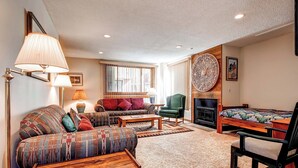 A cozy living room with a fireplace, patterned sofas, and a coffee table. - A Downtown Breck Oasis. Enjoy Convenience with Onsite Pool sh15 (Breckenridge)