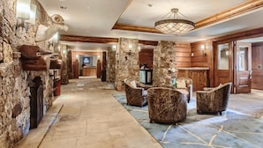 A spacious lobby with stone walls, wooden paneling, and a mix of seating areas including armchairs and a sofa. - Ritz Carlton 1BR Ski-in/out - 2 Queen Beds - Sleeps 4 (Beaver Creek)