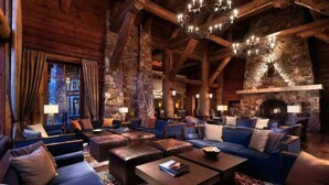 A log cabin-style interior with a stone fireplace, multiple seating areas, and a chandelier. - Ritz Carlton 1BR Ski-in/out - 2 Queen Beds - Sleeps 4 (Beaver Creek)