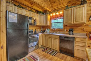 A kitchen with wooden cabinets, a stainless steel refrigerator, a dishwasher, and a window with a 'Welcome' sign. - Privacy~Sunset View~Pet Friendly~Pool Table~Air Hockey (SEVIERVILLE)