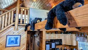 A wooden cabin interior with a staircase, kitchen area, and two teddy bears on the railing. - Privacy~Sunset View~Pet Friendly~Pool Table~Air Hockey (SEVIERVILLE)