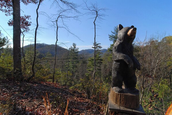 A bear statue in a forested area with a clear view of the surrounding landscape.