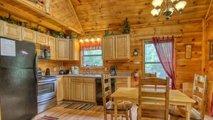 A wooden cabin kitchen with a refrigerator, stove, sink, and wooden dining table with chairs. - Privacy~Sunset View~Pet Friendly~Pool Table~Air Hockey (SEVIERVILLE)