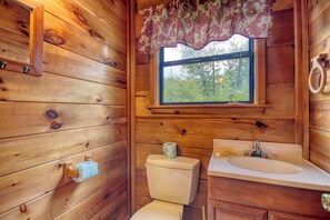 A wooden cabin bathroom with a toilet, sink, and window. - Privacy~Sunset View~Pet Friendly~Pool Table~Air Hockey (SEVIERVILLE)