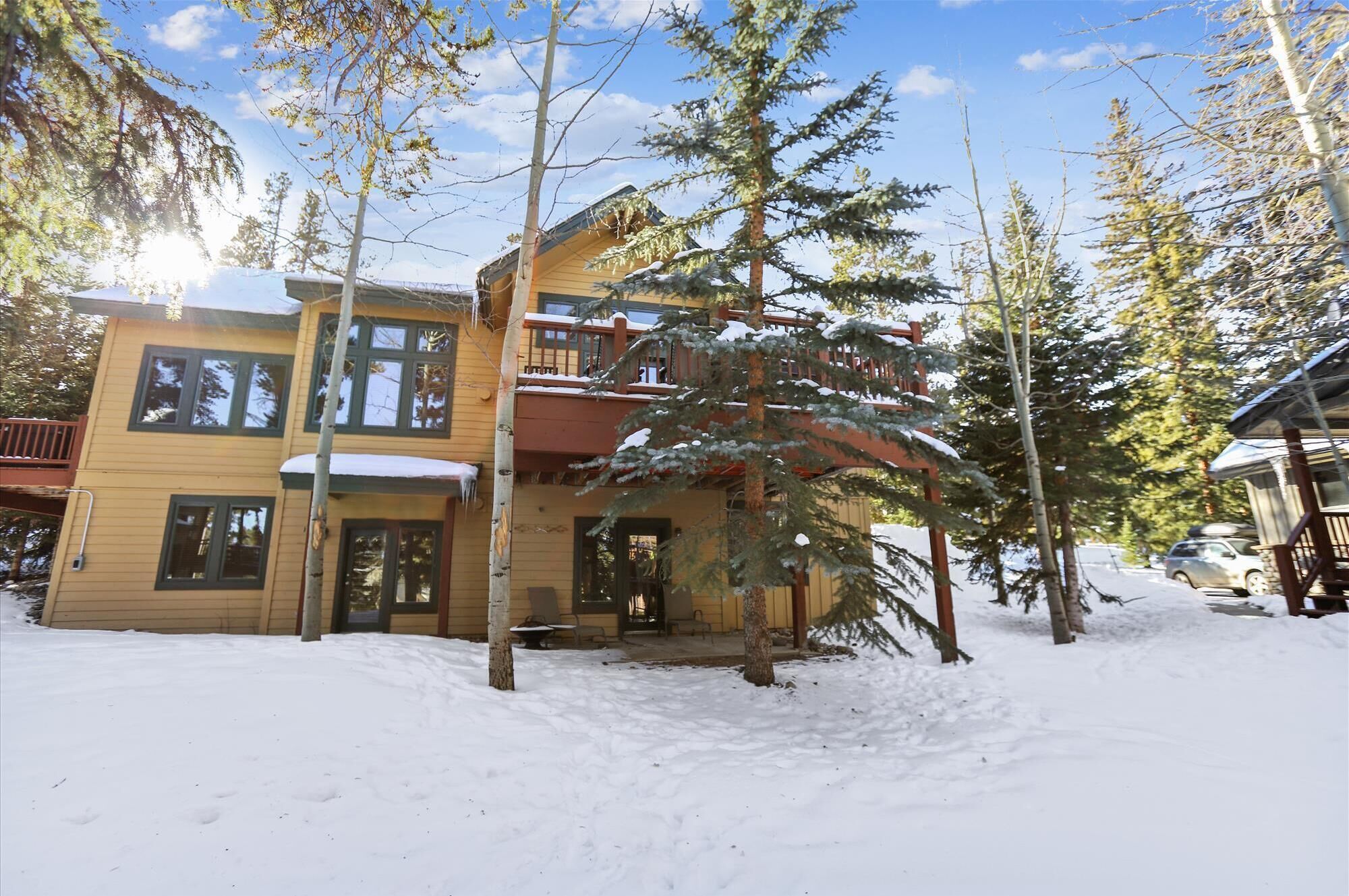 A multi-story wooden building with a balcony, surrounded by snow-covered ground and trees.