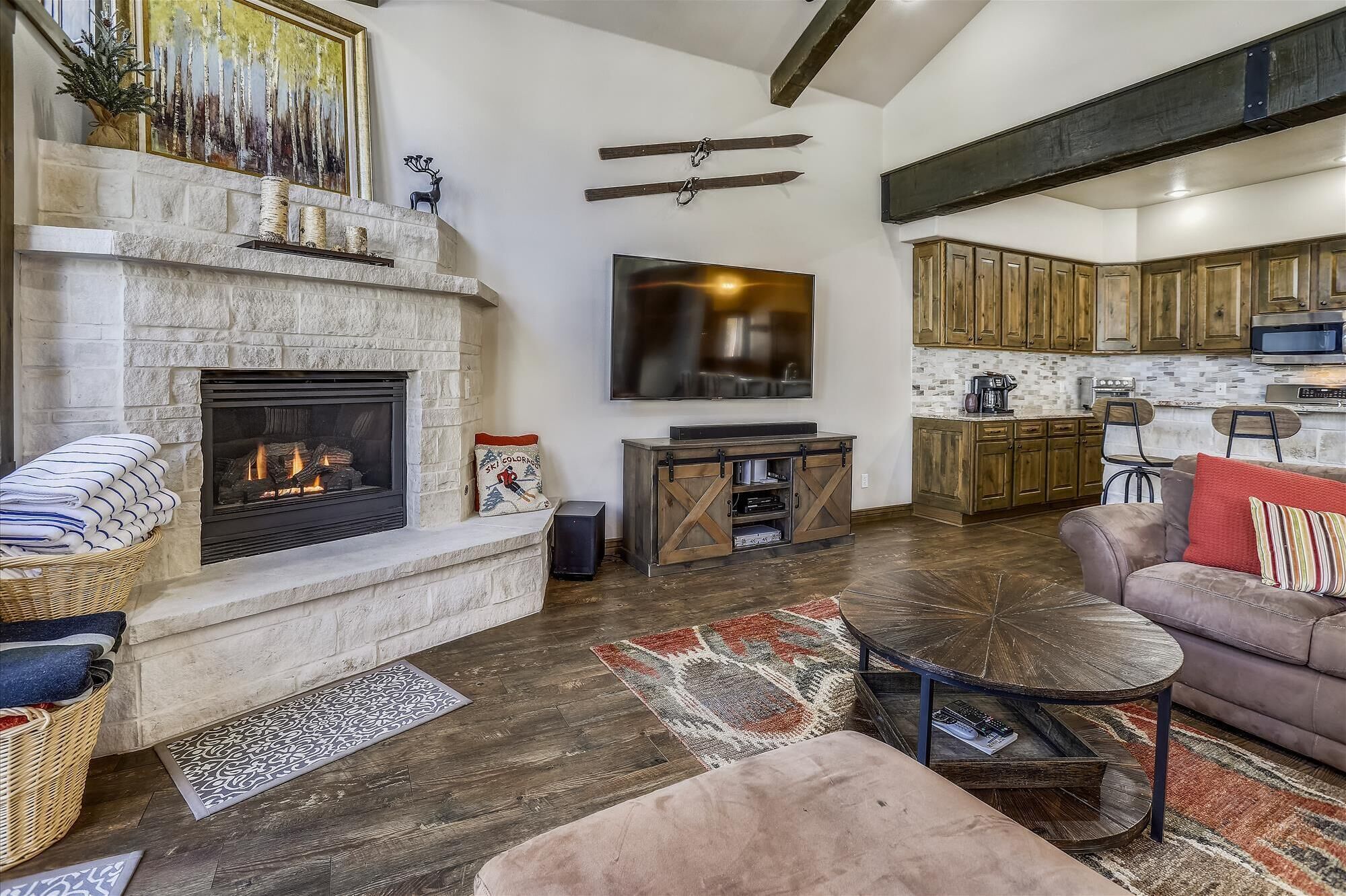 Amplia sala de estar con chimenea, televisor de pantalla plana, sofá acogedor y zona de cocina con armarios de madera.