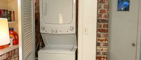 A compact laundry room with a washer and dryer, a bookshelf with books, and a door with a small window.