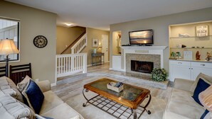 Una sala de estar con chimenea, televisor y escalera que lleva a otro nivel.