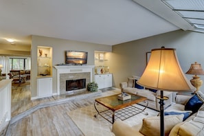 Una sala de estar con chimenea, televisor y sofá.