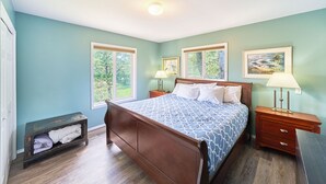 A bedroom with a wooden bed, two bedside tables with lamps, a nightstand, a window, and a small shelf with folded towels. - HOT TUB, Game Room, Walk to Beach, Fenced Yard, Dogs Ok (45th) (Long Beach)