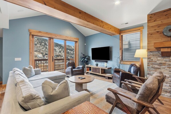 A living room with a sofa, chairs, a coffee table, a TV, and a fireplace.