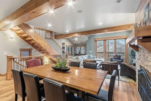 A spacious living area with a wooden staircase, a dining table with chairs, and a cozy seating arrangement.