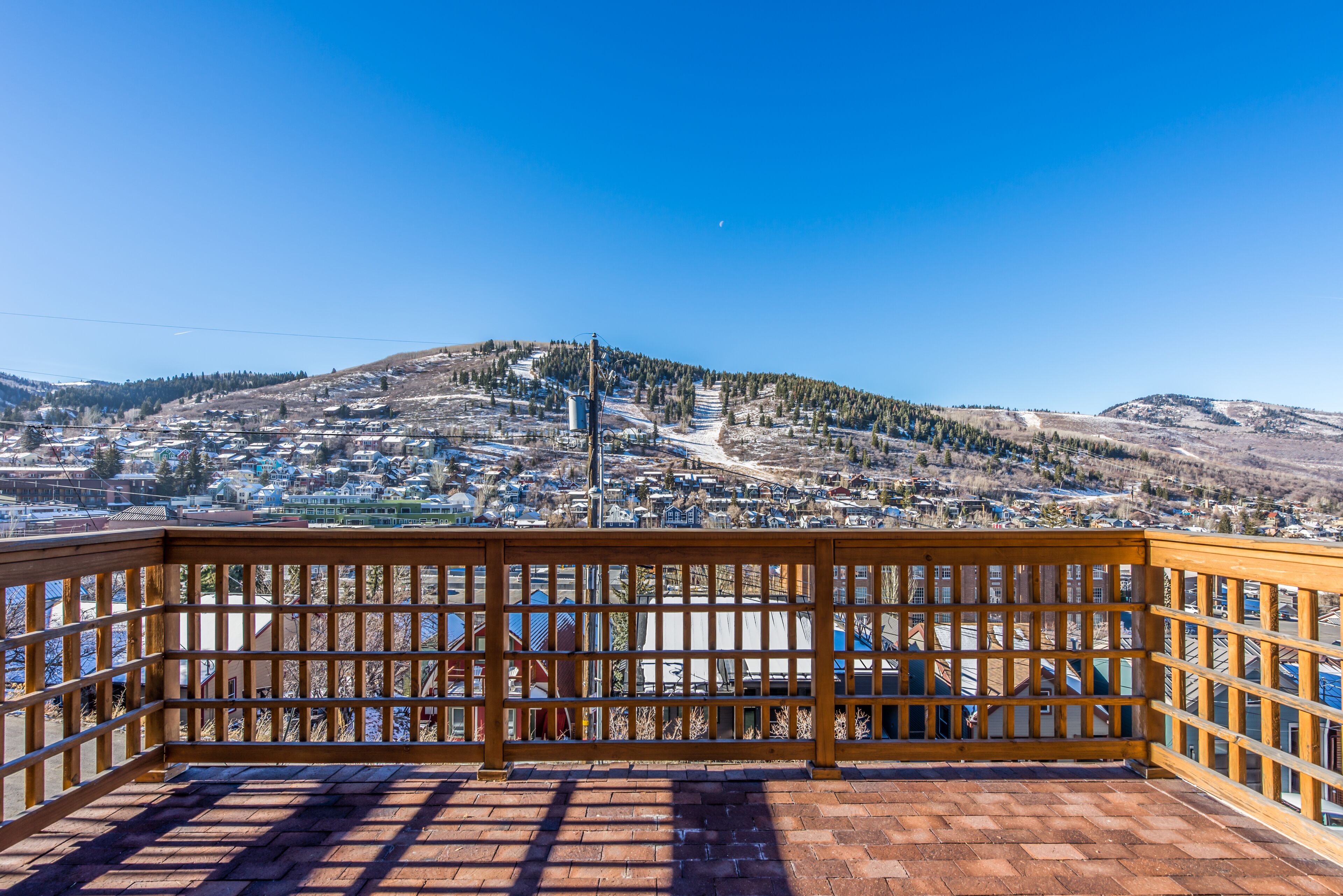 A balcony with a view of a town and a hill.