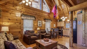 A log cabin interior with a living room, dining area, and kitchen. - Pigeon Forge | Pet Friendly | Mountain Views | Hot Tub | Fireplace | WiFi (Pigeon Forge)