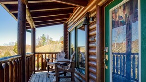A wooden deck with Adirondack chairs and a view of the surrounding landscape. - Pigeon Forge | Pet Friendly | Mountain Views | Hot Tub | Fireplace | WiFi (Pigeon Forge)