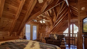 A cozy attic bedroom with a wooden ceiling, a large bed, a ceiling fan, and a view of the outdoors through a window. - Pigeon Forge | Pet Friendly | Mountain Views | Hot Tub | Fireplace | WiFi (Pigeon Forge)