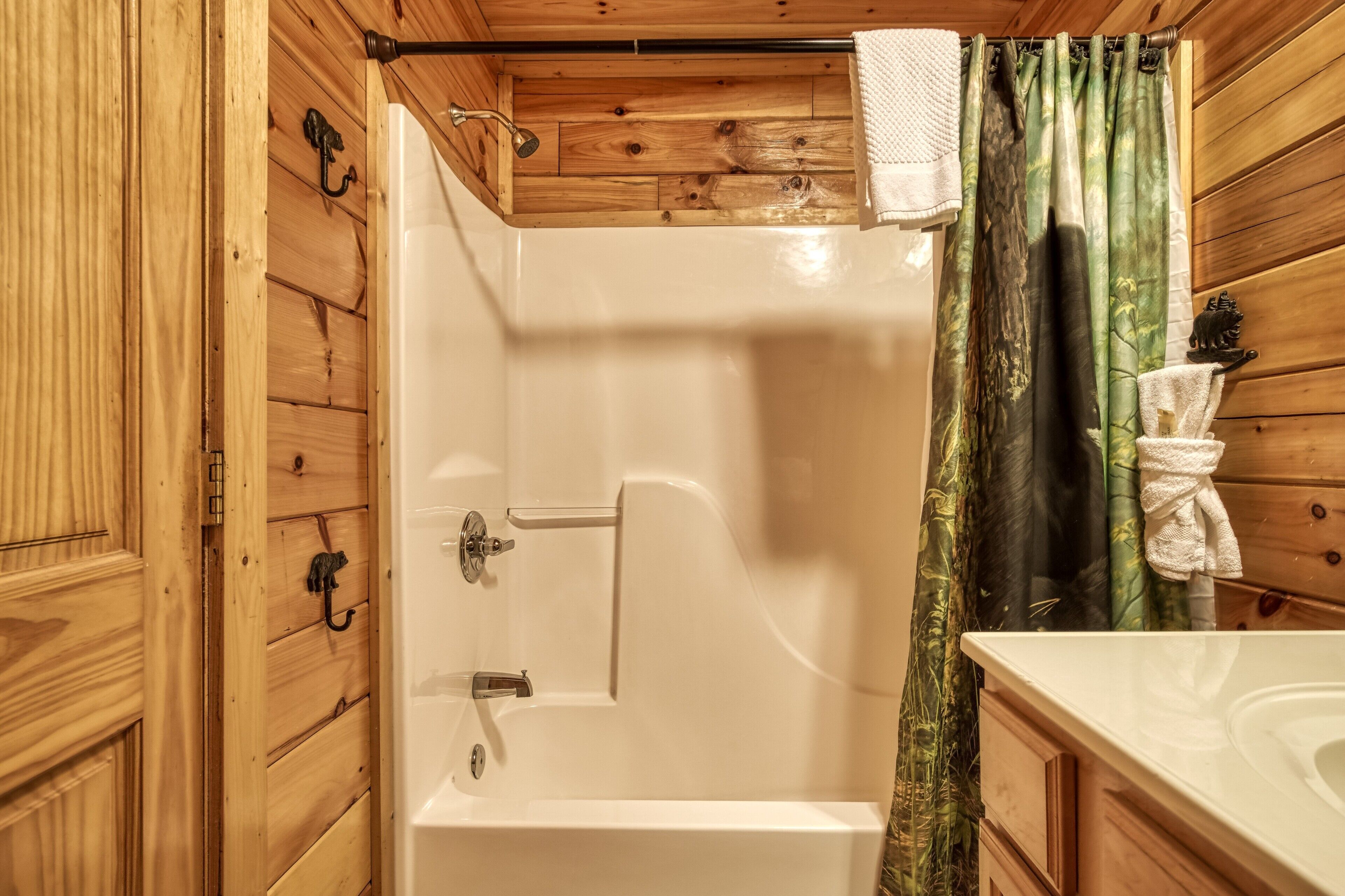 A wooden cabin bathroom with a bathtub, shower, and a wooden vanity with a sink.