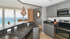 A kitchen with granite countertops, stainless steel appliances, and a view of the ocean.