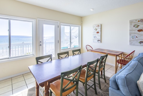 A dining area with a table and chairs, a view of the ocean, and a wall with fish artwork. - Gulf Front Condo, Elevator, Near Shops and Restaurants-Dune Allen Beach (Santa Rosa Beach)