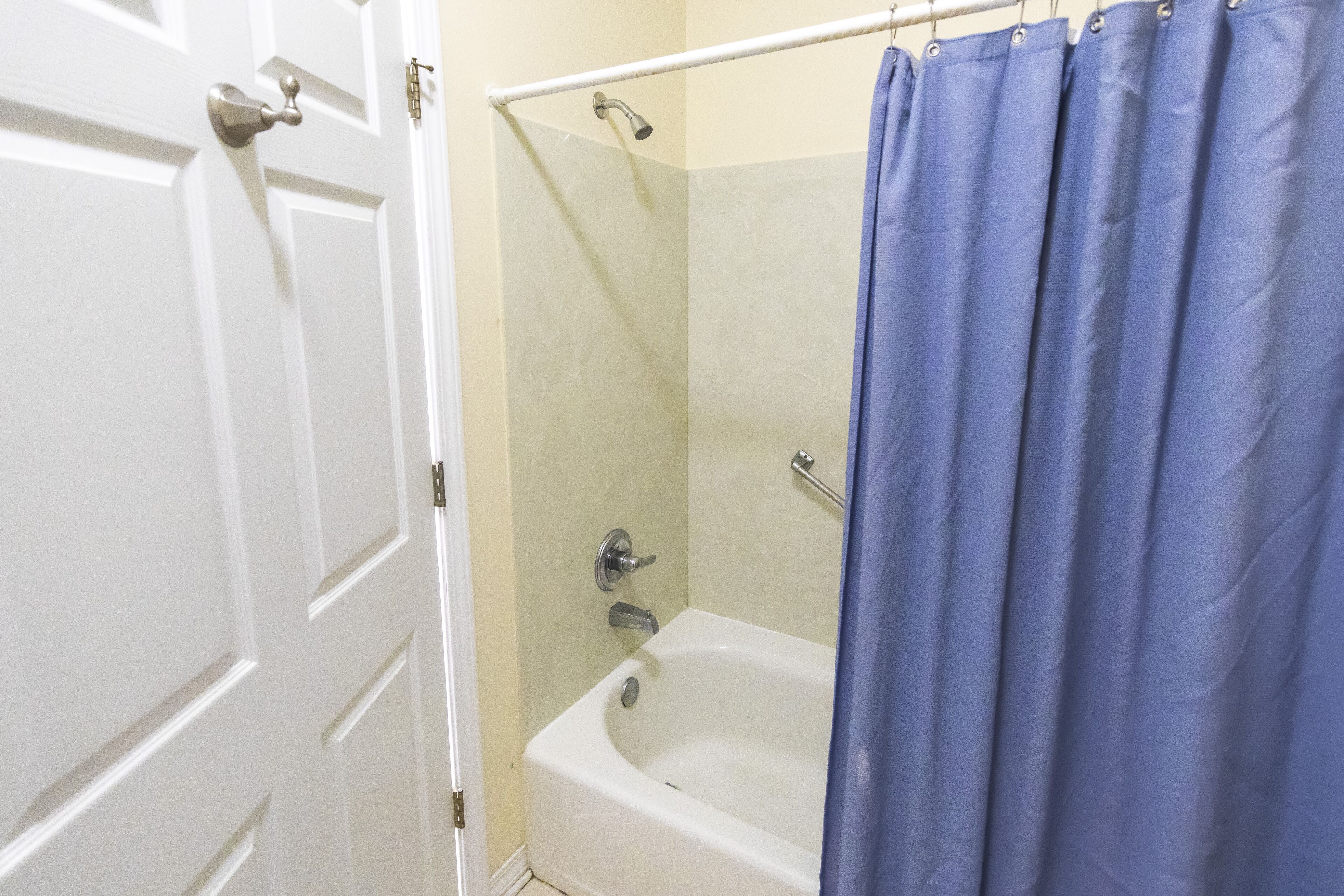 Une salle de bain avec une baignoire, une douche et une porte blanche.