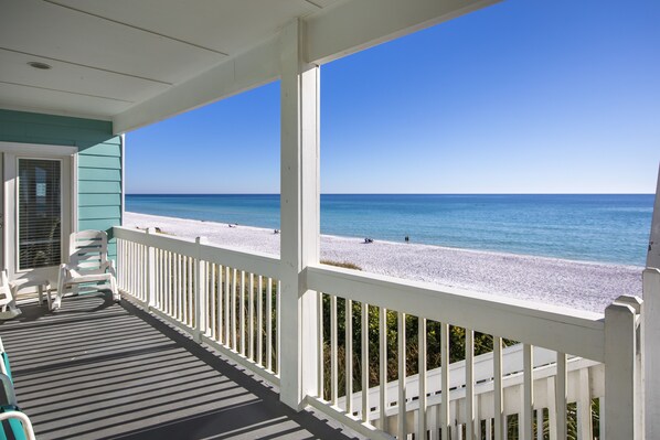 A covered porch with a view of a beach.