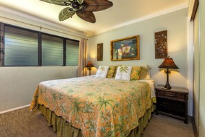 A bedroom with a large bed, a ceiling fan, and two wall-mounted lamps.