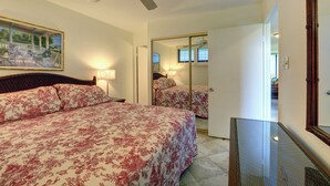 Une chambre à coucher avec un lit, un ventilateur de plafond, un tableau et un miroir.