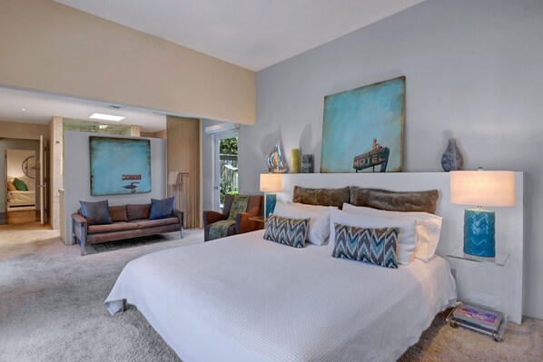 A spacious bedroom with a large bed, a sofa, and a painting of a boat on the wall. - Palmera - Tahquitz River Estates Private Paradise! (Palm Springs)