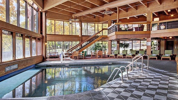 Une piscine intérieure avec un revêtement intérieur en bois, un panneau indiquant qu’il est interdit de plonger et un escalier menant à un niveau supérieur.
