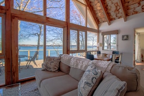 Relax in a serene lakeside setting with expansive views and a cozy living area featuring a comfortable sofa and dining space.