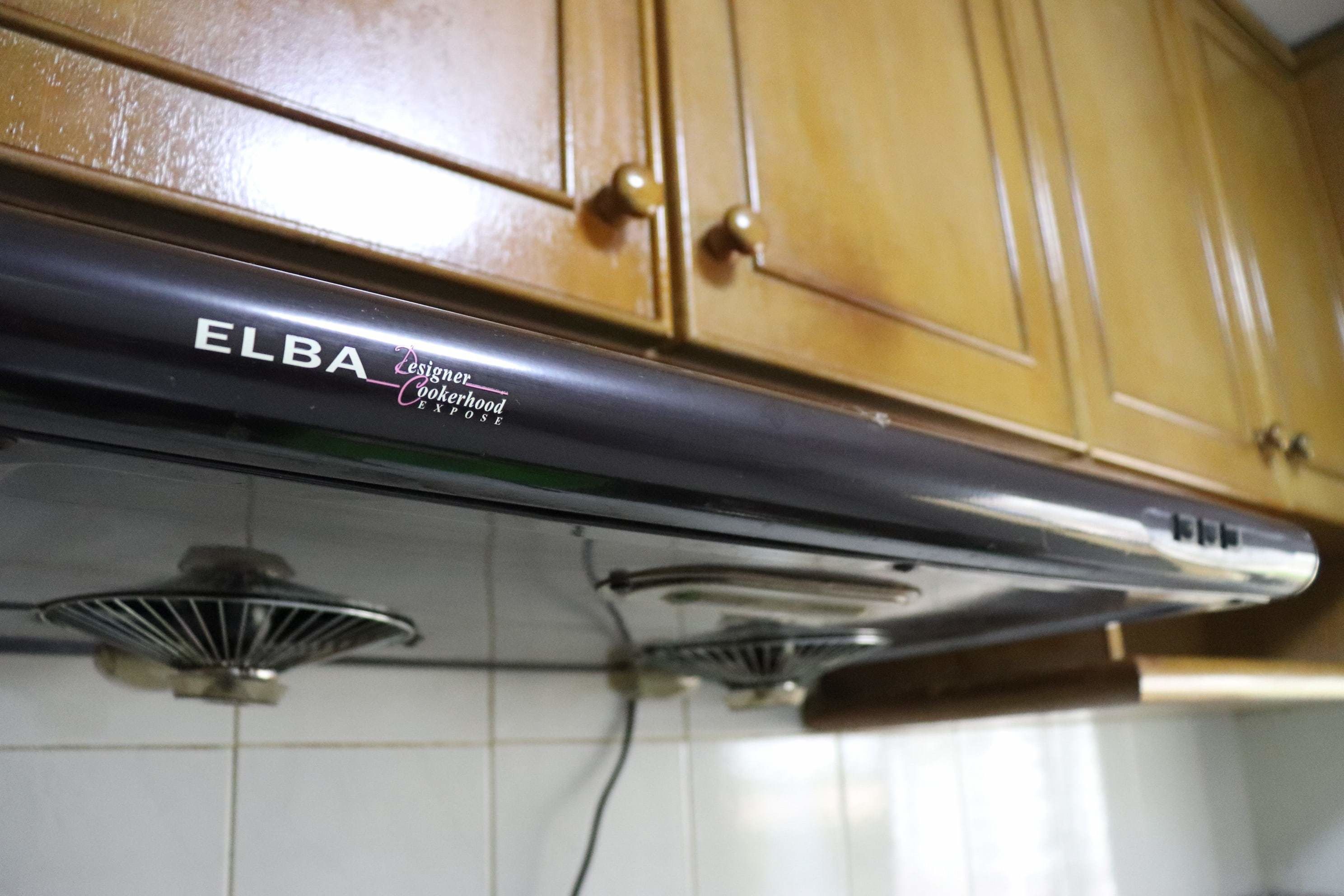 Cocina con armarios de madera y una campana extractora de acero inoxidable con el texto 'ELBA Designer Cookery'.
