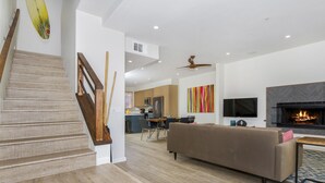 Una sala de estar moderna con una escalera, una chimenea y un comedor.