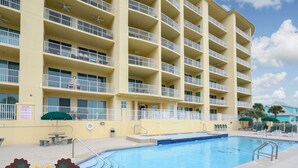 Un hôtel à plusieurs étages doté de balcons, d’une piscine et d’un espace extérieur aménagé pour s’asseoir.