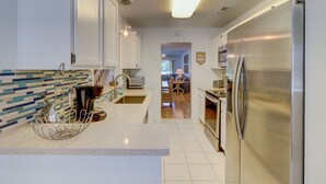 A modern kitchen with white cabinets, a stainless steel refrigerator, and a tiled backsplash.