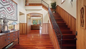 A spacious hallway with a wooden staircase and a view into a living area. - Drake Park Villa - River Front on Mirror Pond & Drake Park, Exquisite, Gourmet Kitchen (Bend)