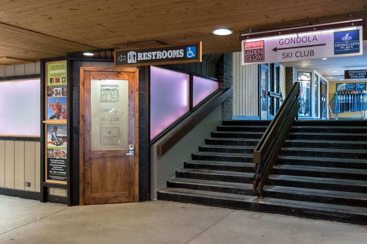A staircase leading to a ski club with a sign indicating restrooms nearby.