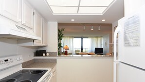 A modern kitchen with white cabinetry, a built-in stove, and a refrigerator.