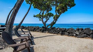 A beachside seating area with chairs and a rocky wall, overlooking the ocean. - 🏖️Top Floor Kona Condo w/ Ocean Views + Full A/C (Kailua Kona)