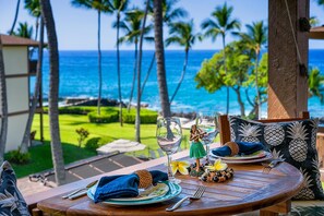 Une table dressée pour deux personnes, avec vue sur l’océan et les palmiers.