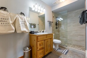 Ein modernes Badezimmer mit einem Holzbadezimmermöbel, einer Duschkabine aus Glas und einem großen Spiegel.