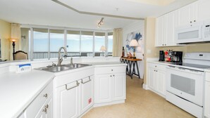 A modern kitchen with white cabinetry, a built-in oven, and a microwave. - Spacious beachfront end condo w/large private balcony! 🌴 (Destin)