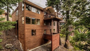 Eine mehrstöckige Holzhütte mit einem Balkon, umgeben von Bäumen.